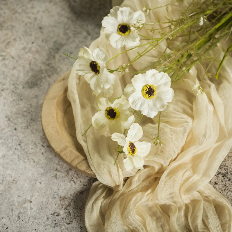 White flowers with yellow centers on a beige fabric against a textured stone background
