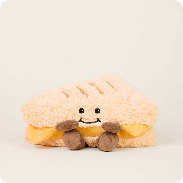 Plush toy shaped like a grilled cheese sandwich with a smiley face on a white background