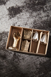 Decorative items including a hand, tombstone, and skull in a box on a textured surface