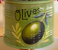 A close-up of a green ceramic vase painted with the word 'Olives' in black script, a large green and black olive illustration, and yellow olive leaves.