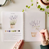 Person painting lavender in a sketchbook with color swatches