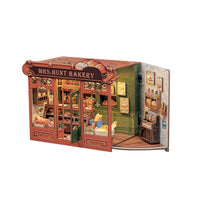 A miniature book nook model of 'Mrs. Hunt Bakery' with detailed interior scenes, miniature furniture, and decorative elements, shown against a plain white background.