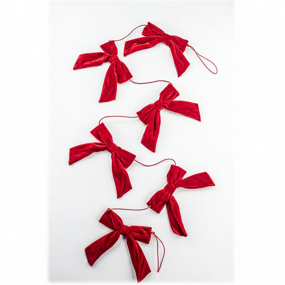 A red velvet bow garland made of five tied velvet bows connected by thin red strings, laid out on a plain white background.