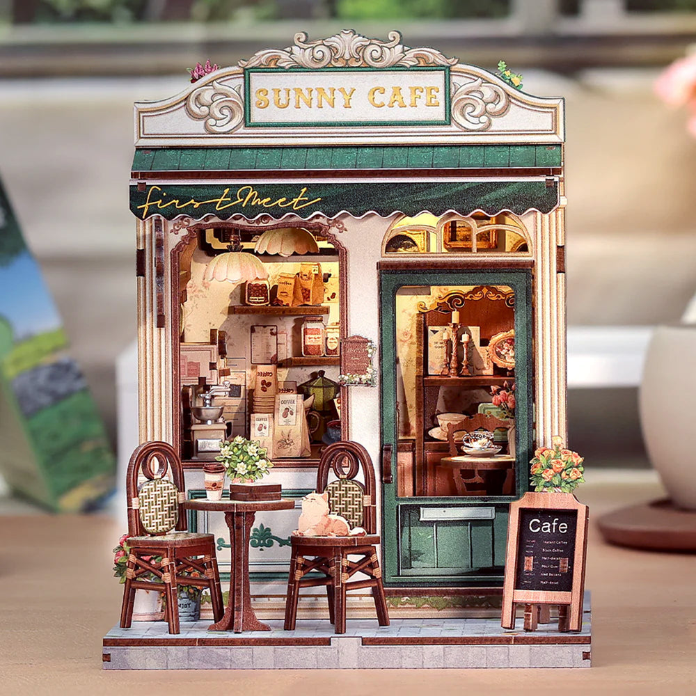 Model of a cafe with 'Sunny Cafe' sign on top, featuring furniture and decor inside.
