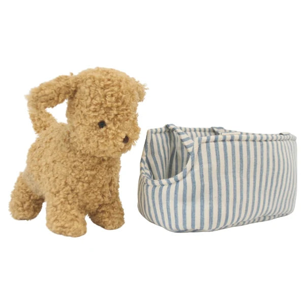 Stuffed dog toy next to a striped fabric carrier on a white background