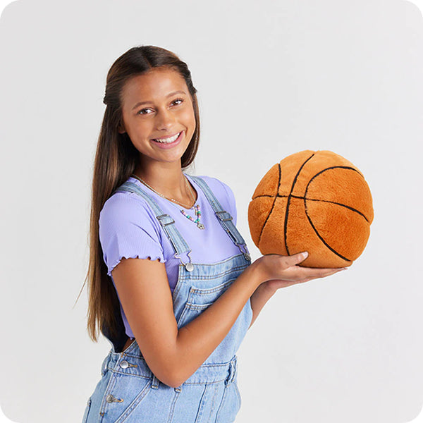 Young girl holding a plush basketball against a white background